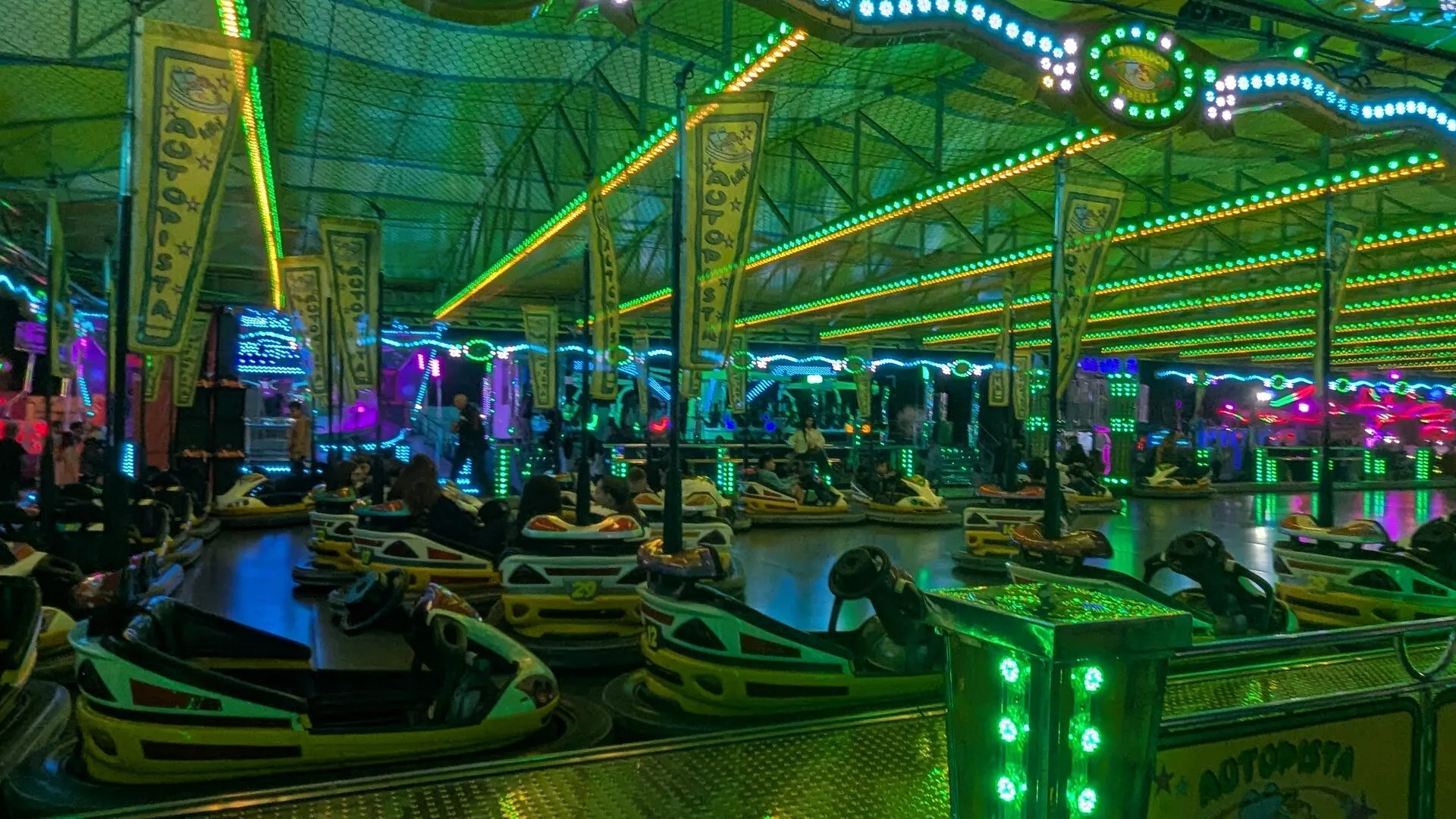 Interior de la pista de coches de choque de la feria de Dénia, con los coches aparcados bajo la estructura de luces